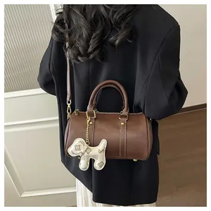 Back view of a woman wearing a brown Boston handbag with a cute dog charm