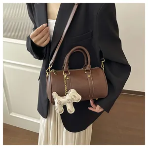 Detail of brown Boston pillow bag with dog charm and contrast white stitching.