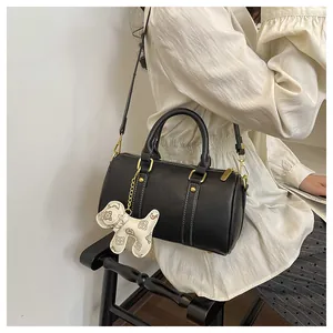 Elegant black Boston pillow bag for women with dog charm shown on a model's shoulder