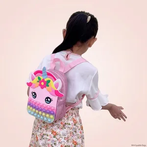 Little girl wearing a pink unicorn backpack for kids featuring colorful pop-it fidget toy panel