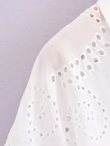 Close-up of intricate white eyelet embroidery on a feminine cotton shirt shoulder detail