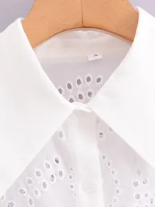 Close-up detail of white embroidered eyelet texture and collar on a cotton shirt