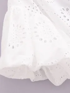 Close-up view of intricate white eyelet embroidery on a feminine puff sleeve shirt