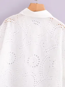 Close-up of a white shirt featuring intricate floral eyelet embroidery detail texture