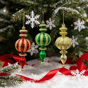 Glittery teardrop Christmas ornaments set hanging on a snow-covered pine tree branch