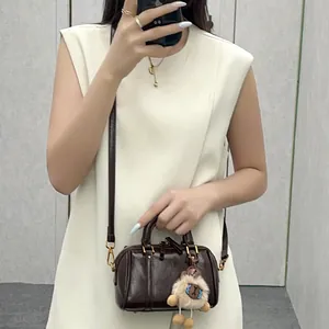 Detail of small brown leather Boston pillow bag with cute sheep plush keychain