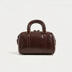Elegant dark brown glossy Boston handbag with a vintage pillow bag silhouette for women