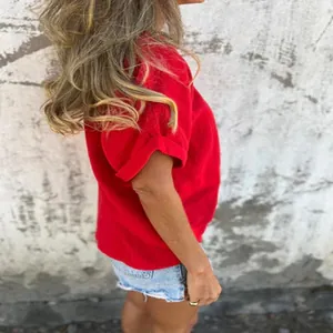 Side view of a vibrant red short-sleeved cotton T-shirt worn by a model on a wall