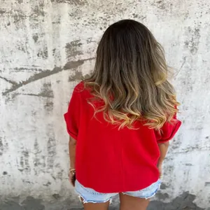 Back view of a vibrant red short-sleeved summer T-shirt for women against a wall