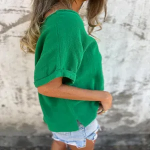 Side view showing the textured green fabric and side slit of this short-sleeved top.
