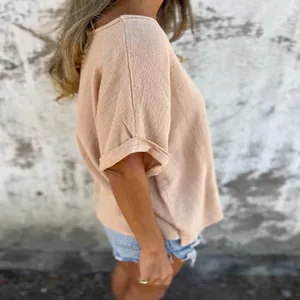 Side profile detail view of a soft apricot cotton t-shirt with rolled-up sleeves