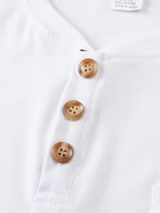 Macro view showing the brown buttons and soft white cotton texture of a men's Henley shirt