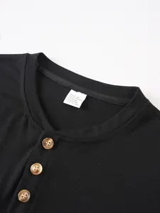 Close-up of black round neck T-shirt with three brown buttons and size tag