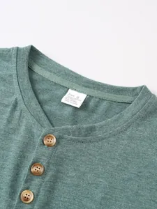 Detailed view of green henley neck t-shirt with three buttons and material tag