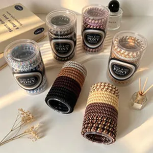 Set of diverse leopard and wave pattern elastic hair ties in clear cylinder packaging.