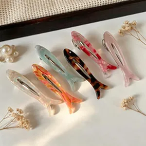 Set of colorful fish-shaped acetate hair clips arranged on a decorative white surface