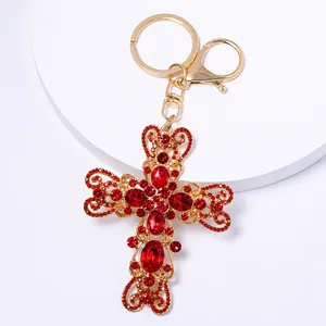 Vue détaillée d'un porte-clés croix en forme de cœur doré avec strass rouges éclatants.