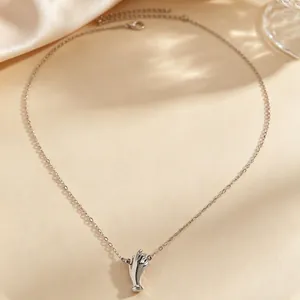Macro view of creative silver hand gesture pendant necklace resting on silk background