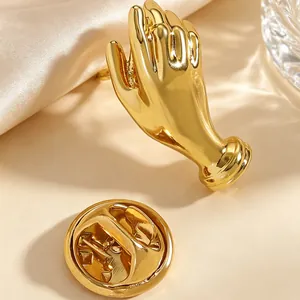 Detailed view of an artistic golden hand-shaped brooch pin with a butterfly clutch back