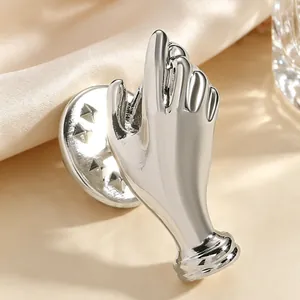 Close-up of a unique artistic silver hand-shaped brooch designed to hold a flower vase