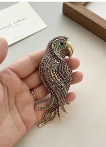Close-up of a large vintage parrot brooch with colorful rhinestones held in hand