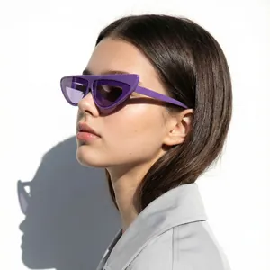 Detail view of stylish purple irregular cat-eye sunglasses worn by a fashion model