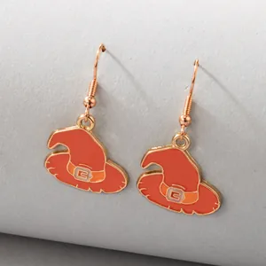 Macro view of orange enamel witch hat earrings for Halloween on neutral gray background