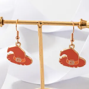 Close-up detail of orange Halloween witch hat enamel drop earrings on a gold stand