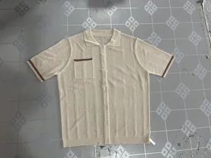 Close-up view of a beige men's hollow knit shirt featuring a button-up front and brown trim.