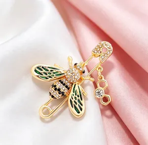 Detailed macro view of a gold bee brooch with green enamel wings and rhinestones