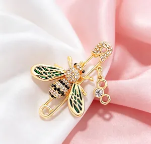 Close-up of a golden bee brooch with green enamel wings and sparkling rhinestones on satin.