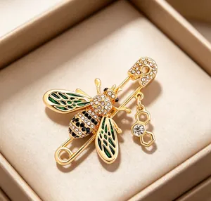 Detailed close-up of a gold-toned bumblebee brooch with green enamel wings and rhinestones.