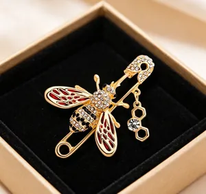 Close-up of golden honey bee brooch with red enamel and rhinestones in gift box