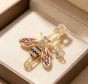 Detailed view of a gold-toned bee brooch with rhinestones and red enamel wings in a box.