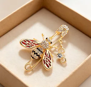 Macro view of high-quality gold bee brooch with red enamel wings and sparkling rhinestones