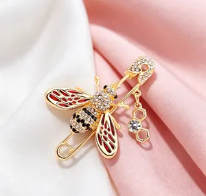 Detailed close-up view of a gold-toned bee safety pin brooch with sparkling crystals.