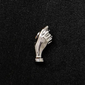 Kreative silberne Hand-Brosche mit glänzendem Metallfinish auf schwarzem Textil
