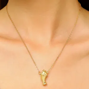 Nahaufnahme einer filigranen goldene Halskette mit Hand-Anhänger, getragen von einem Model.