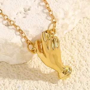 Close-up detail of a gold hand-shaped bouquet brooch on a textured white rock background.