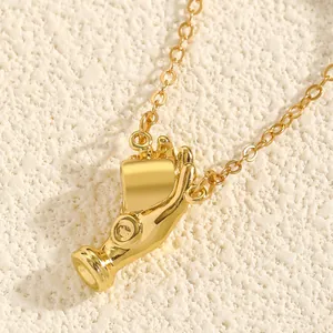 Detailed view of a creative gold hand-shaped pendant necklace on a textured background.