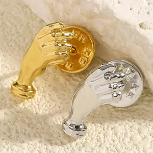 Detailaufnahme künstlerischer Hand-Broschen in Gold und Silber auf rauem Steinuntergrund.