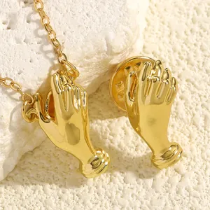 Macro view showing the glossy gold finish of a unique hand-shaped brooch and pendant set