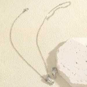 Close-up of a silver-toned necklace featuring a creative hand-holding bouquet pendant