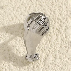 Macro view of a creative silver hand-shaped brooch with a high-shine polished finish