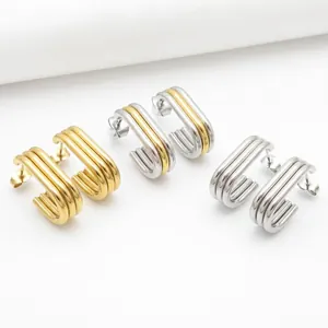 Detail of U-shaped multi-layered stainless steel hoop earrings in gold, silver, and mixed tones.