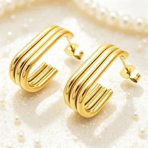Detailed macro view of gold-plated multilayered oval hoop earrings on a pearly surface