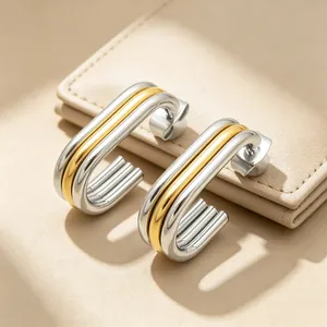 Macro detail of two-tone minimalist oval multi-layer stainless steel earrings on leather