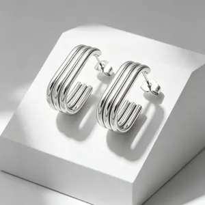 Detailed view of multi-layered silver stainless steel oval hoop earrings on white block