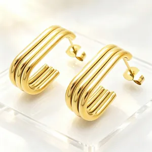Close-up of gold-plated stainless steel oval hoop earrings with multi-layer design details.