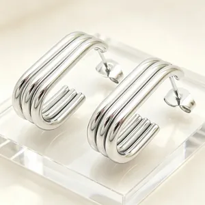 Close-up detail of silver multi-layer stainless steel oval hoop earrings on acrylic block